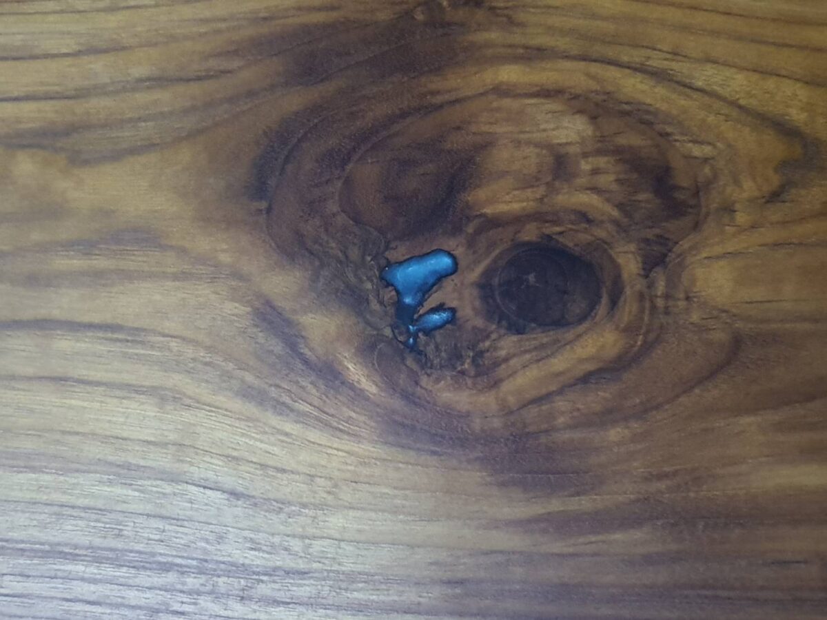 teak wood knot point is filled with blue epoxy